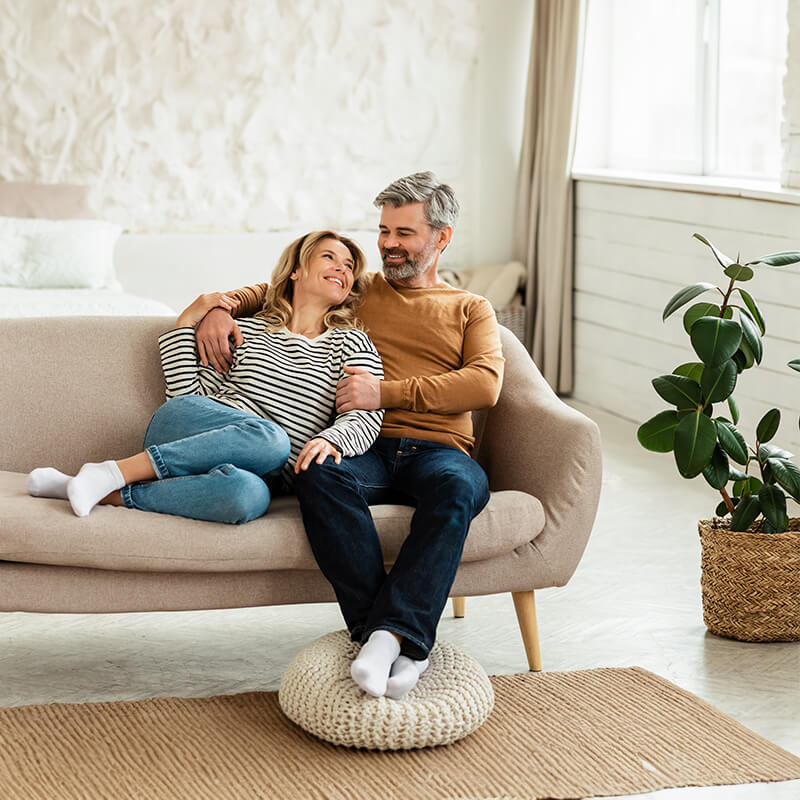 Eine glückliche Familie sitzt auf einem Sofa in einem modern eingerichteten Wohnzimmer, symbolisch für nachhaltiges Wohnen mit Solarenergie