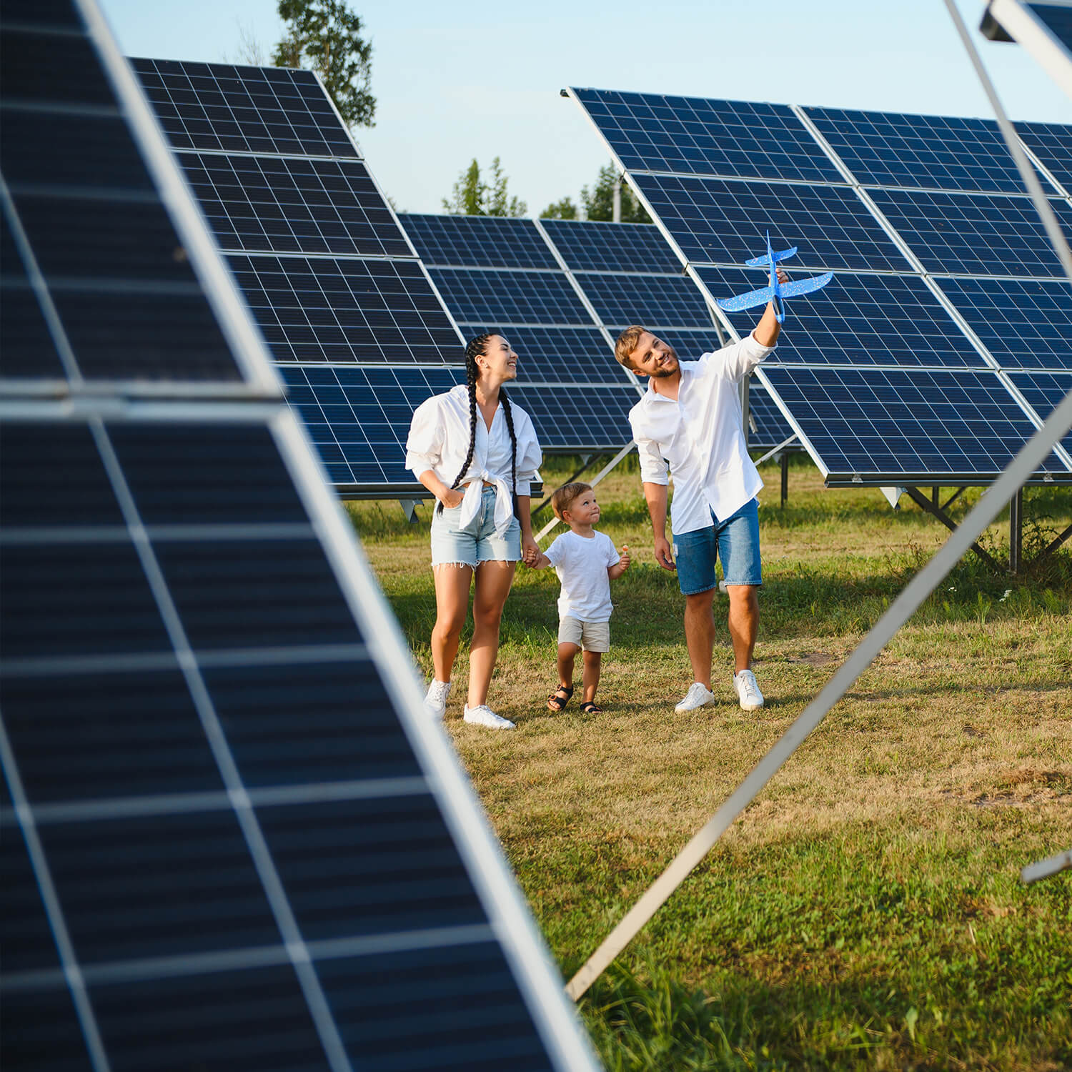 Eltern mit Kind besuchen eine Solarfarm mit großen Solarmodulen, Symbol für erneuerbare Energien
