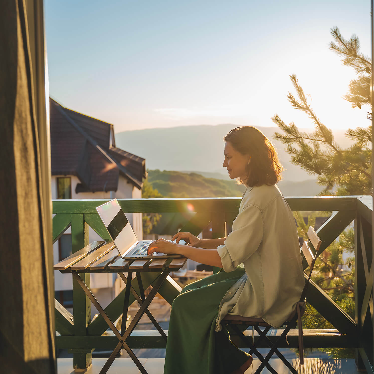 Frau arbeitet auf einem Balkon mit Laptop, betrieben durch nachhaltigen Solarstrom
